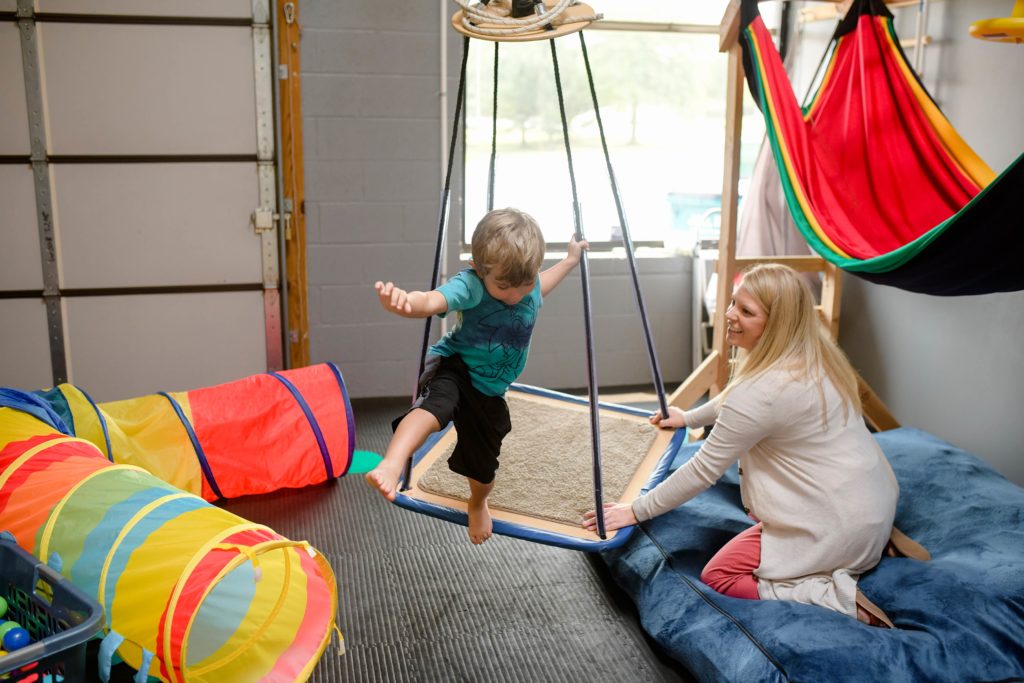 Basal therapies employee playing with child on a swing