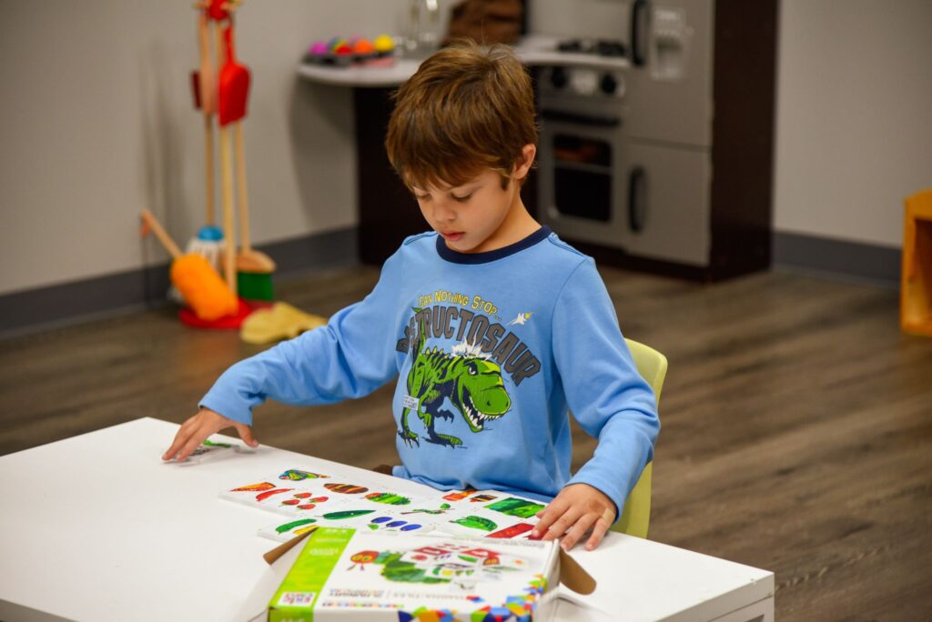 Young child playing with sticker book at Basal Preschool