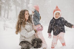 mother playing with two children in snow