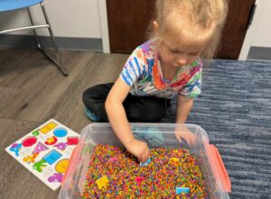 young girl playing with a box of sensory toys for sensory integration therapy